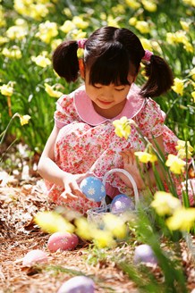 Girl collecting Easter eggs from a field 