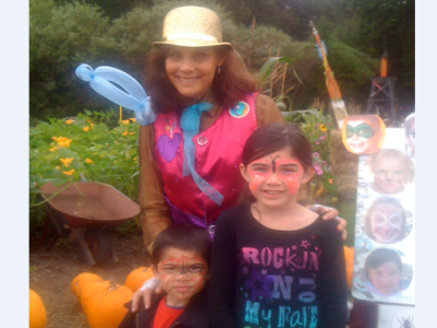 Denise Dutil smiles with two children who had their faces painted during a Pumpkin Festival in California.