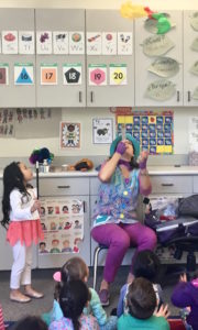 Children's entertainer Denise blows confetti during her Magic Comedy Show at a preschool birthday party.
