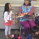 Children's entertainer Denise holds a book during her Magic Comedy Show at a preschool birthday party.