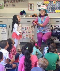 A girl is curious about what Denise is holding during her Magic Comedy Show at a preschool birthday party.
